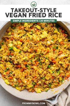 a bowl filled with rice and vegetables on top of a white table next to spoons