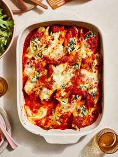 a white casserole dish filled with pasta and sauce on top of a table