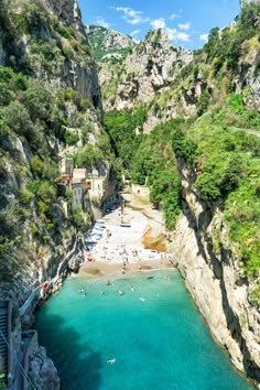 the beach is surrounded by cliffs and blue water, with people swimming in the water