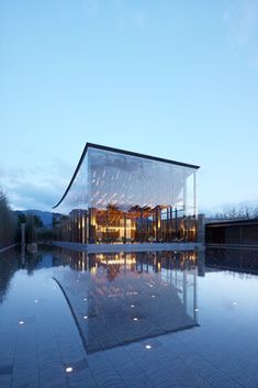 a large glass building sitting on top of a pool in front of a blue sky