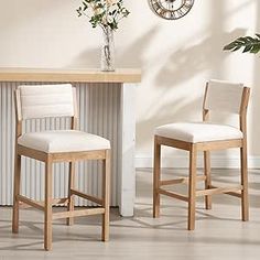 two white chairs sitting next to each other in front of a table with flowers on it