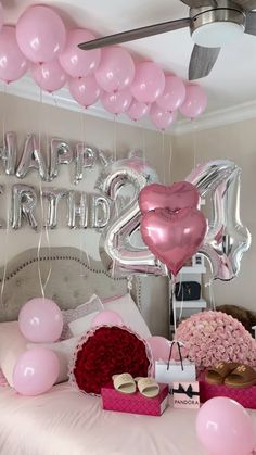 a bed with pink and red balloons on it