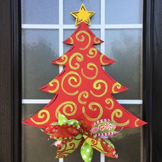 a red christmas tree door hanger on a front door with green and yellow bows