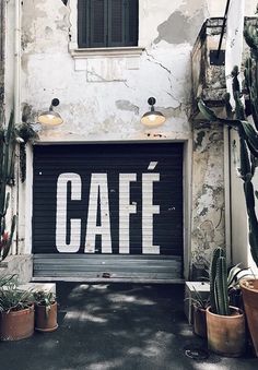 a garage door with the word cafe painted on it in front of some cacti