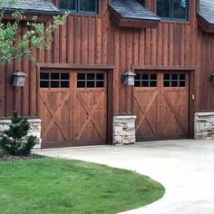 two brown garage doors in front of a large wooden building with three windows on each side