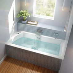 a bathtub with water running from the faucet to the side and a window above it