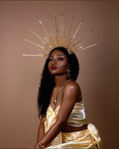 a woman in a yellow dress with a gold crown on her head, sitting down