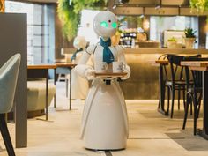 a robot holding a tray with food in it's hands while sitting at a table