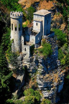 an old castle built into the side of a rocky cliff surrounded by trees and bushes