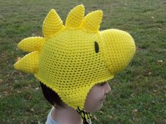 a child wearing a yellow crocheted hat with a dragon on it