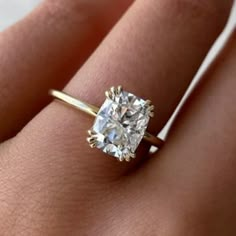 a woman's hand with a diamond ring on top of her finger and an engagement band