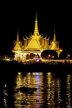 the building is lit up at night and reflecting in the water with lights on it