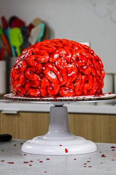 a large red cake sitting on top of a white cake plate covered in icing