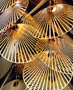 an array of umbrellas hanging from the ceiling in front of a black wall with lights