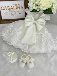 a bouquet of white flowers and baby shoes are on the floor next to a framed photograph