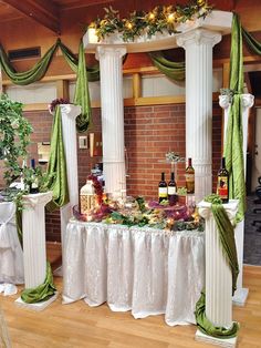 the table is set up with wine bottles and other items on it, along with green drapes