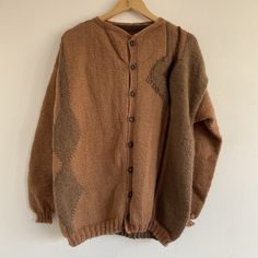 "Vintage 80s Brown Hand Knitted Abstract Button Up Wool Cardigan  Beautiful 1980s geometric patterned cardi! Mid weight, chunky handmade knit. Rusty brown terracotta with beige abstract patterns.  Button down with crew neck collar.  Hippie / cottage / boho style.  Recommended fit: Large / up to UK 16 or over sized on smaller sizes.  In good vintage condition.  Possibly wool & acrylic blend - no care labels. Soft material - not itchy.  See all measurements below. Measurements: Length: 27\" Chest: Brown Knitted Casual Cardigan, Brown Knit Casual Cardigan, Casual Brown Knitted Cardigan, Oversized Brown Cardigan With Buttons, Brown Knitted Outerwear, Oversized Brown Wool Sweater Coat, Oversized Brown Buttoned Sweater, Cozy Brown Knitted Cardigan, Brown Knit Cardigan With Fair Isle Pattern