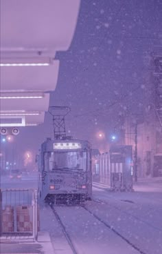 a train traveling down tracks next to a snow covered platform with lights on and people standing near it