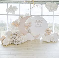 a baby shower with balloons, moon and clouds on the floor in front of a large window