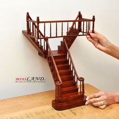 a hand holding a miniature model of a stair case on top of a wooden table