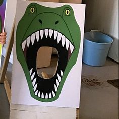 a child holding up a cardboard box with a dinosaur face on it and mouth open