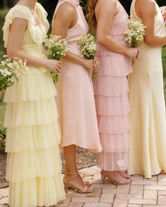 four bridesmaids in pastel colored dresses standing next to each other