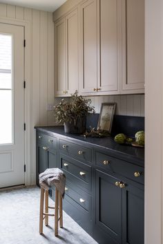 a kitchen with white cabinets and black counter tops, two stools in the foreground