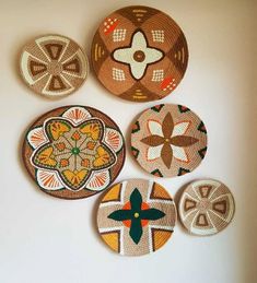 four woven coasters are arranged on a white surface, each decorated with different designs