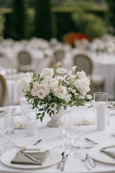 a table with white flowers and silverware is set for a formal dinner or reception