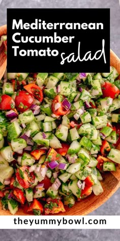 a wooden bowl filled with cucumber tomato salad next to a black sign that says mediterraneann cucumber tomato salad