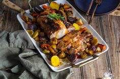 a white plate topped with chicken, potatoes and carrots next to a blue casserole dish