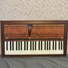 an old wooden piano sitting on top of a gray sheet covered floor next to a wall