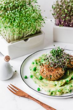 a plate topped with meat patties covered in pea sauce and garnished with sprouts