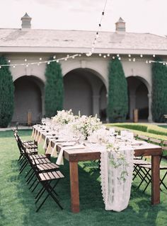 a long table with white flowers and greenery is set up for an outdoor dinner