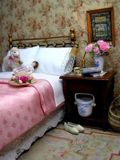 a doll house bedroom with pink bedding and floral wallpaper