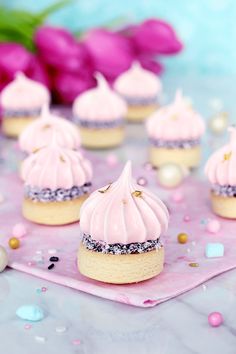 pink frosted cupcakes with sprinkles and pearls on a table