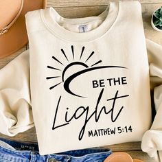 a t - shirt with the words be the light on it next to some shoes