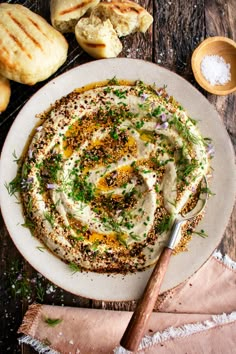 a white plate topped with hummus and herbs