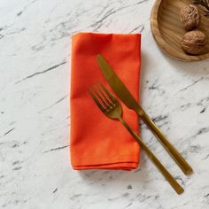 an orange napkin with a gold fork on it