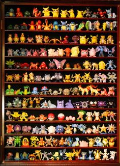 a large collection of pokemon figurines on display in a wooden case with glass doors