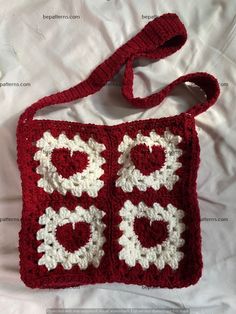 a crocheted red and white purse on top of a bed next to a pillow