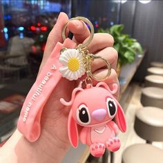 a person holding a pink keychain with a flower on it