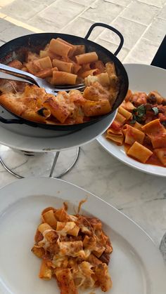 two plates with food on them sitting on a table next to another plate full of food