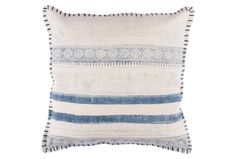 a blue and white striped pillow with fringes on the front, sitting against a white background