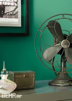 a metal fan sitting on top of a table next to a box and other items