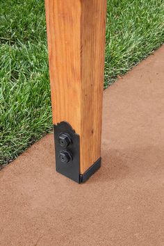 a wooden post with a black latch on the end and grass in the back ground