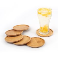 six wooden coasters and a glass filled with lemonade on a white background,