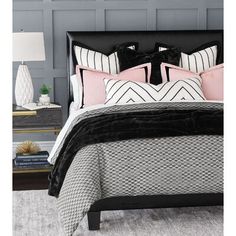 a black and white bed in a bedroom with pink pillows on the headboard, along with two nightstands