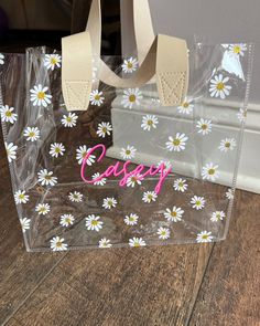 a clear plastic bag with white daisies on it and the word happy written in pink