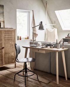 a living room filled with furniture and a wooden table topped with a computer desk next to a window